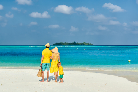 Family on beach, young couple in yellow with three year old boy. Summer vacation at Maldives.の写真素材