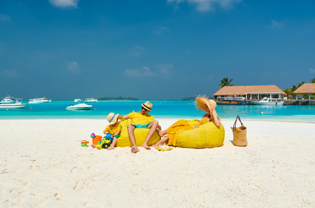 Family on beach, young couple in yellow with three year old boy. Summer vacation at Maldives.の写真素材