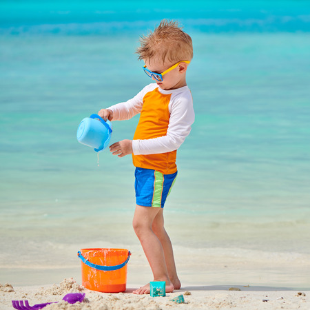 Three year old toddler boy playing with beach toys on beach. Summer family vacation at Maldives.の写真素材