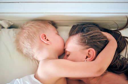 Three year old toddler boy sleeping on pillow with motherの写真素材