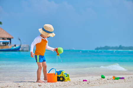 Three year old toddler boy playing with beach toys on beach. Summer family vacation at Maldives.の写真素材