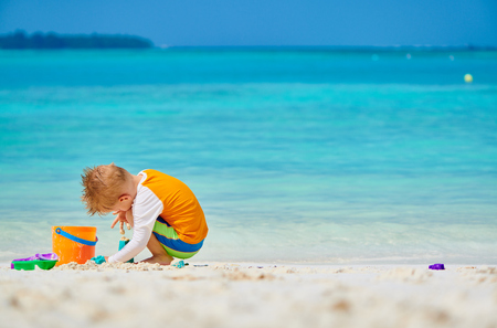 Three year old toddler boy playing with beach toys on beach.  Summer family vacation at Maldives.の写真素材