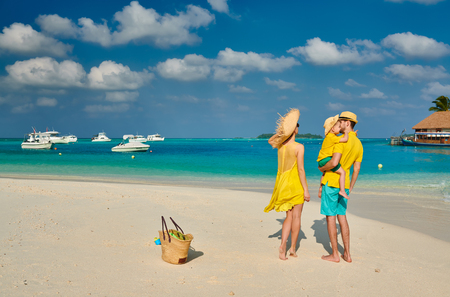 Family on beach, young couple in yellow with three year old boy. Summer vacation at Maldives.の写真素材