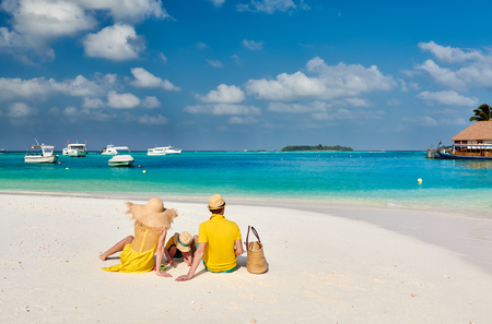 Family on beach, young couple in yellow with three year old boy. Summer vacation at Maldives.の写真素材