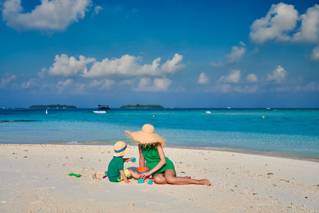 Family on beach, woman in green dress with three year old boy. Summer vacation at Maldives.の写真素材
