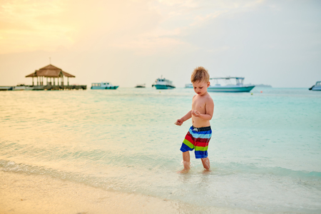 Three year old toddler boy on beach at sunset. Summer family vacation at Maldives.の写真素材