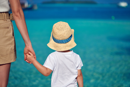 Three year old toddler boy on beach holding mother's hand. Summer family vacation at Maldives.の写真素材