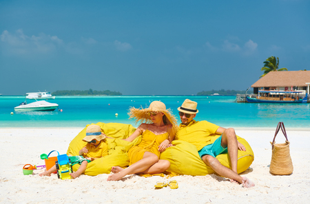 Family on beach, young couple in yellow with three year old boy. Summer vacation at Maldives.の写真素材