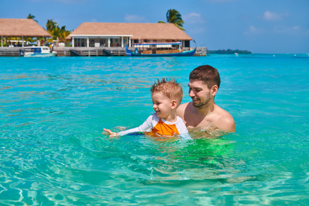 Three year old toddler boy learns to swim with father. Summer family vacation at Maldives.の写真素材