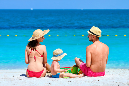 Family on beach. Two year old toddler boy playing with beach toys with mother and father on beach.の写真素材