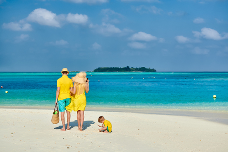 Family on beach, young couple in yellow with three year old boy. Summer vacation at Maldives.の写真素材
