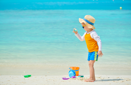 Three year old toddler boy playing with beach toys on beach. Summer family vacation at Maldives.の写真素材