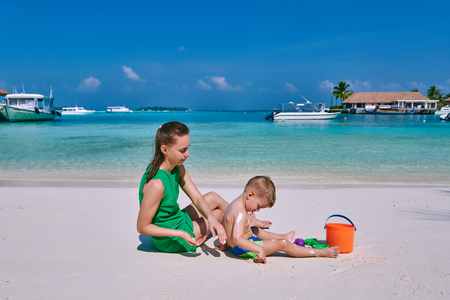 Woman applying sun screen protection lotion on boy's back. Summer vacation at Maldives.の写真素材