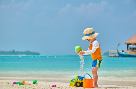 Three year old toddler boy playing with beach toys on beach. Summer family vacation at Maldives.の写真素材