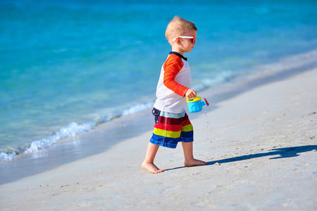 Two year old toddler boy playing with beach toys on beachの写真素材