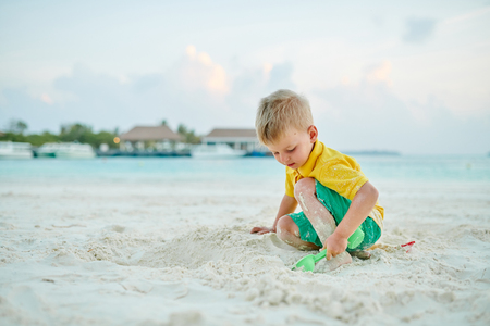 Three year old toddler boy playing with beach toys on beach. Summer family vacation at Maldives.の写真素材