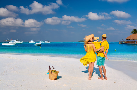 Family on beach, young couple in yellow with three year old boy. Summer vacation at Maldives.の写真素材
