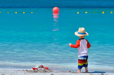 Two year old toddler boy playing with beach toys on beachの写真素材