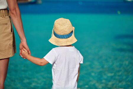 Three year old toddler boy on beach holding mother's hand. Summer family vacation at Maldives.の写真素材