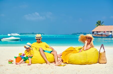 Family on beach, young couple in yellow with three year old boy. Summer vacation at Maldives.の写真素材