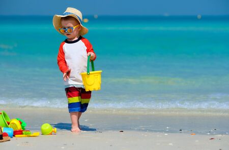 Two year old toddler boy playing with beach toys on beachの写真素材