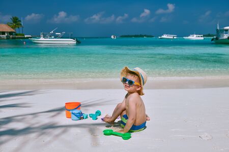 Three year old toddler boy playing with beach toys on beach.  Summer family vacation at Maldives.の写真素材