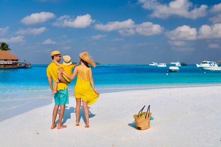 Family on beach, young couple in yellow with three year old boy. Summer vacation at Maldives.の写真素材