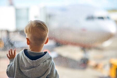 Two year old boy at the airport looking at planeの写真素材