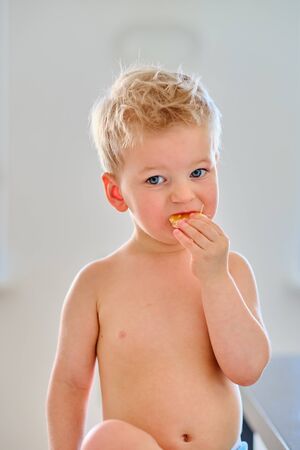 Two year old boy eating orange fruitの写真素材