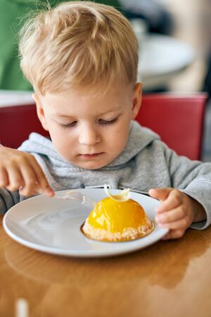 Two year old boy eating dessert in cafeの写真素材