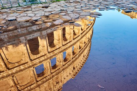 Cobblestone brick paved wet street with Colosseum reflection in Rome, Italyの写真素材