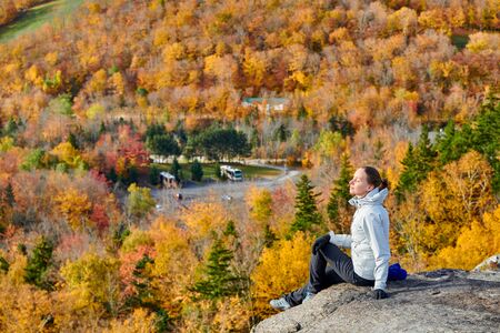 Woman hiking at Artist's Bluff in autumn. Fall colours in Franconia Notch State Park. White Mountain National Forest, New Hampshire, USAの写真素材