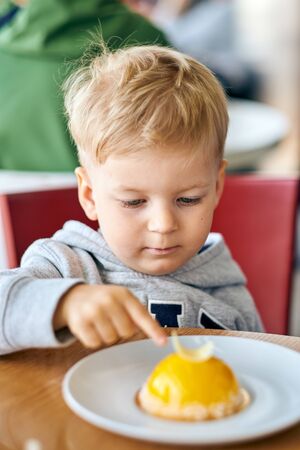 Two year old boy eating dessert in cafeの写真素材