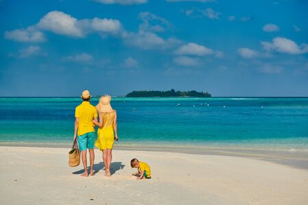 Family on beach, young couple in yellow with three year old boy. Summer vacation at Maldives.の写真素材