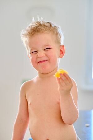 Two year old boy eating sour fruitの写真素材