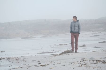 Lone man at beach, foggy autumn day. USA Pacific coast landscape, Californiaの写真素材