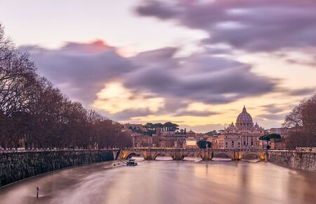 St. Peter's cathedral and Tiber river with high water at evening with dramatic sunset sky. Saint Peter Basilica in Vatican city with Saint Angelo Bridge in Rome, Italyの写真素材