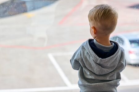 Two year old boy at the airport looking at planeの写真素材