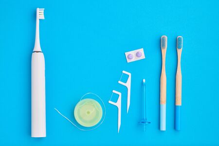 Toothbrushes and oral care tools over blue background top view copy space flat lay. Tooth care, dental hygiene and health concept.の写真素材