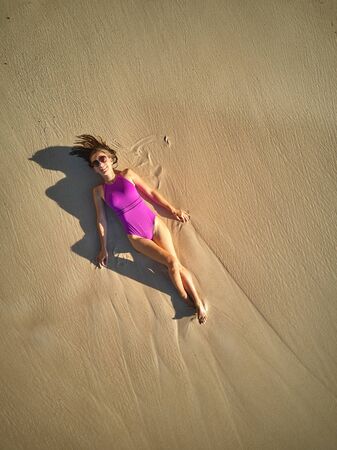 Woman lying down on beach aerial top view drone shot at Seychelles, Maheの写真素材