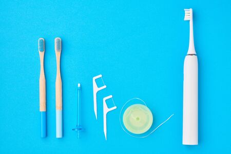 Toothbrushes and oral care tools over blue background top view copy space flat lay. Tooth care, dental hygiene and health concept.の写真素材