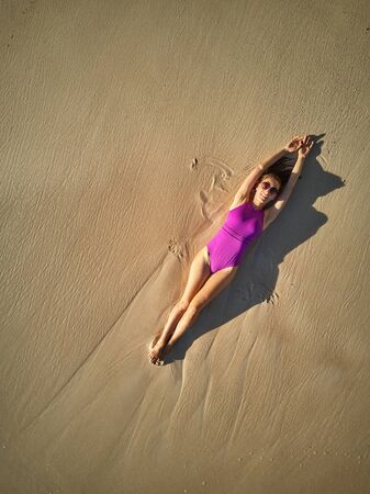 Woman lying down on beach aerial top view drone shot at Seychelles, Maheの写真素材