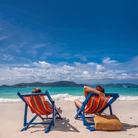Couple on tropical beach in loungers at Thailandの写真素材