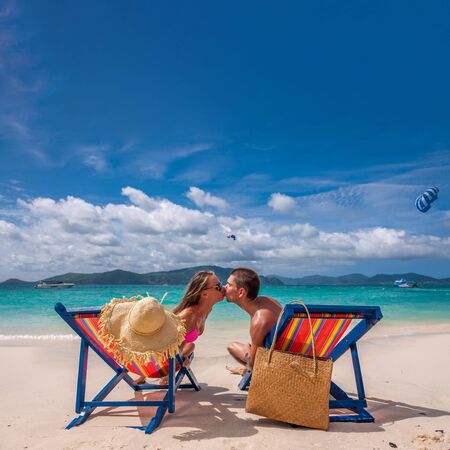 Couple kissing on tropical beach in loungers at Thailandの写真素材