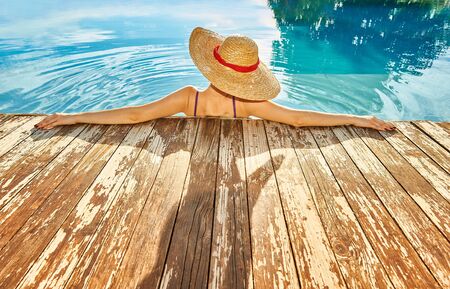 Woman in hat relaxing at the poolの写真素材