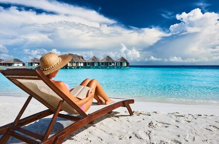 Young woman reading a book at the beachの写真素材