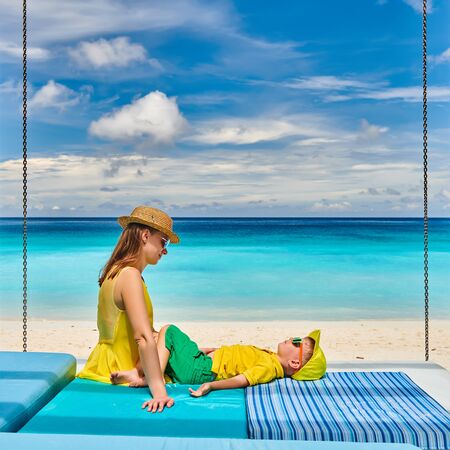Family on beautiful Petite Anse beach, young woman in yellow with three year old toddler boy. Summer vacation at Seychelles, Mahe.の写真素材