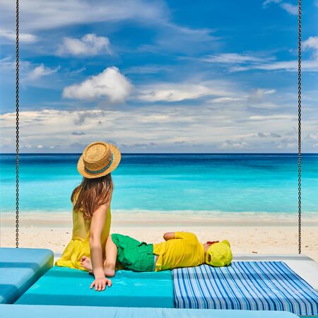 Family on beautiful Petite Anse beach, young woman in yellow with three year old toddler boy. Summer vacation at Seychelles, Mahe.の写真素材