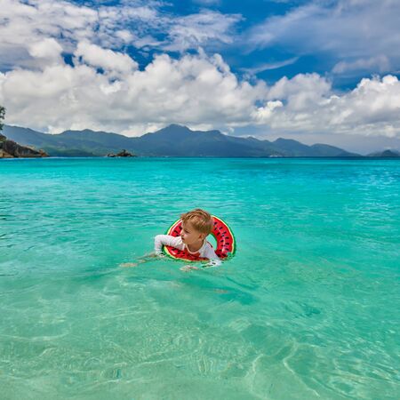 Three year old toddler boy on beach at Seychelles swimming with inflatable ringの写真素材