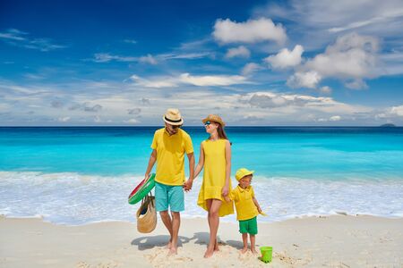 Family on beautiful Petite Anse beach, young couple in yellow with three year old toddler boy. Summer vacation at Seychelles, Mahe.の写真素材